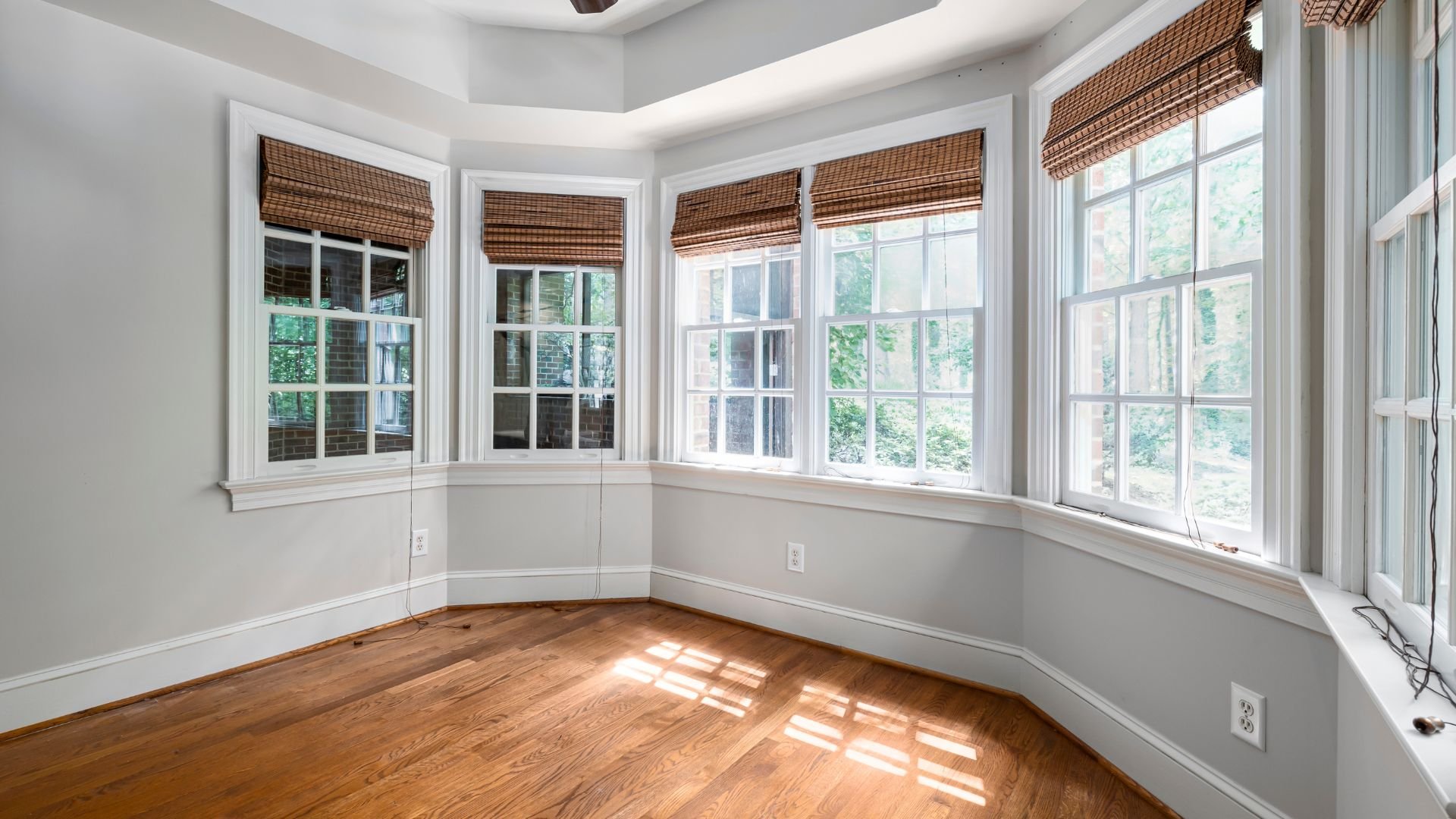 Bright bay window room with wooden floors and woven bamboo shades